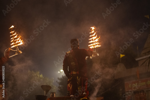 Ganga aarti, Portrait of young priest performing holy river ganges evening aarti at assi ghat in traditional dress with hindu rituals photo