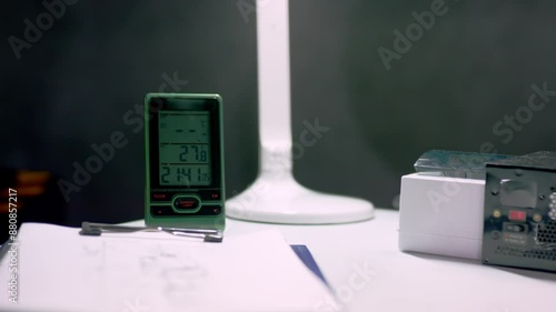 Lamp on office desk provides light to workspace at night. Lamp illuminates workspace during nighttime. Clock on desk shows time in evening