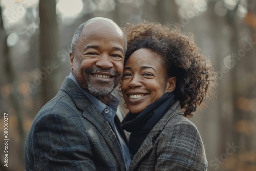 Portrait of a smiling multiethnic couple in their 40s wearing a professional suit jacket in front of backdrop of a mystical forest