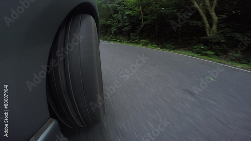 A view of a front right wheel of a car driving on a road with a copy space on the right. 4k 3840x2160, close up and lockdown shot.