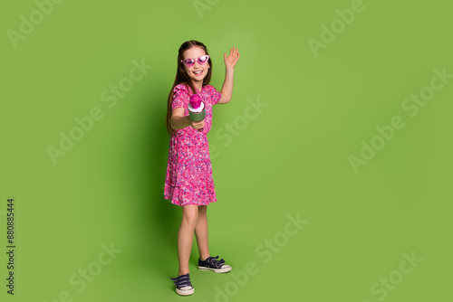 Full size photo of cute schoolgirl give mic you sing empty space wear pink dress isolated on green color background