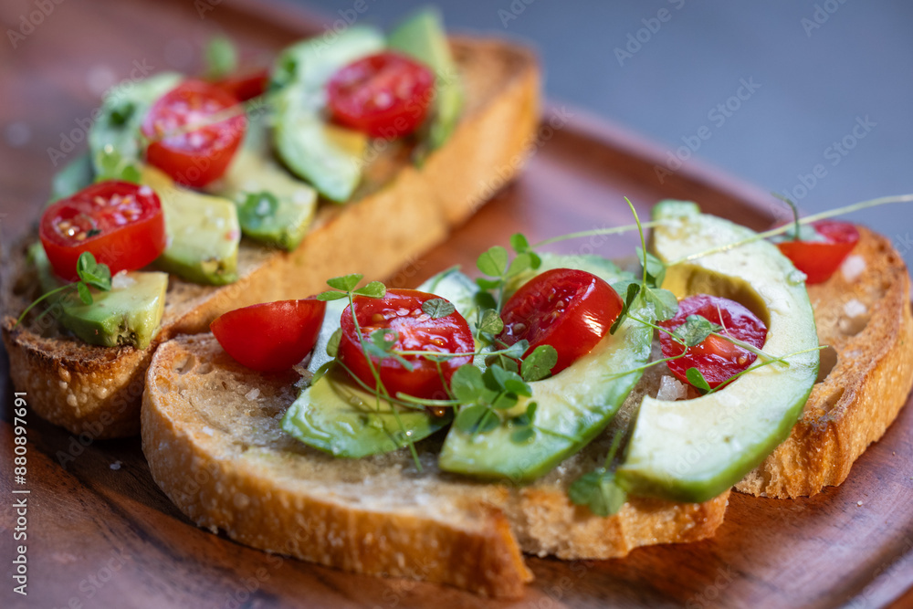 A slice of toasted sour dough bread with avocado and tomato on top A slice of toasted sour dough bread with avocado and tomato on top
