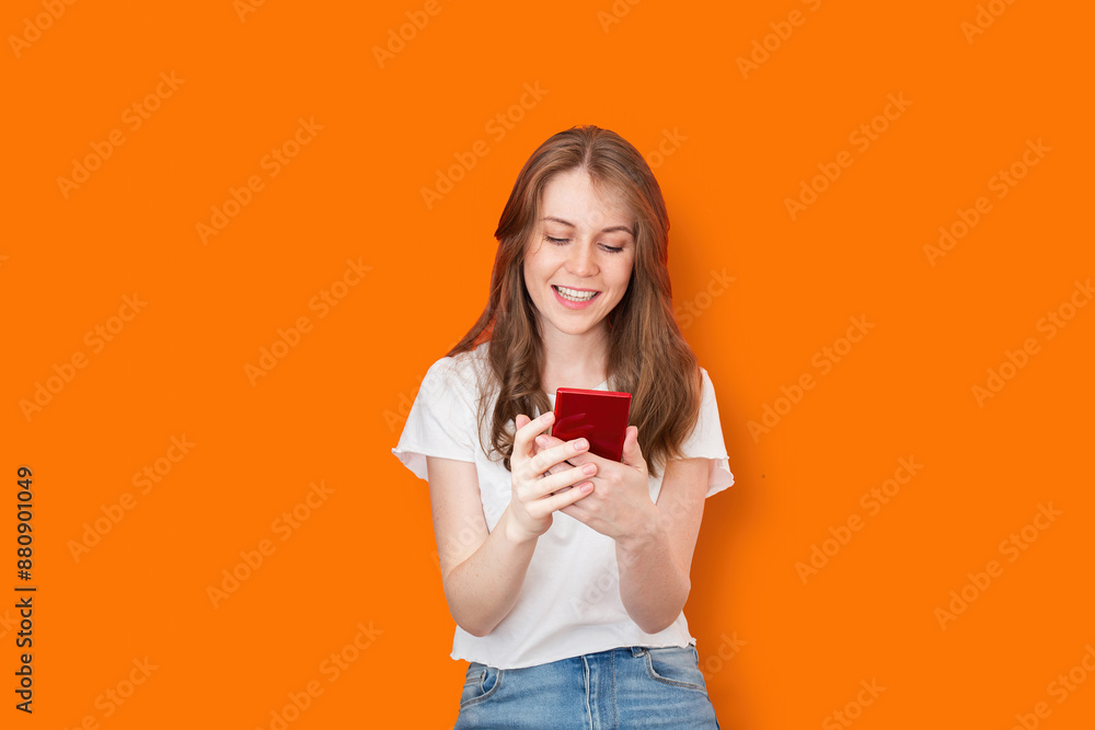 Smiling woman using smartphone on orange background Smiling woman using smartphone on orange background