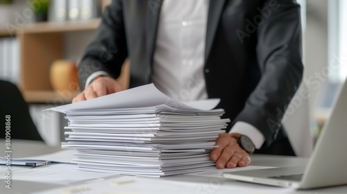 businessman with a big stack of papers on his desk in black suit