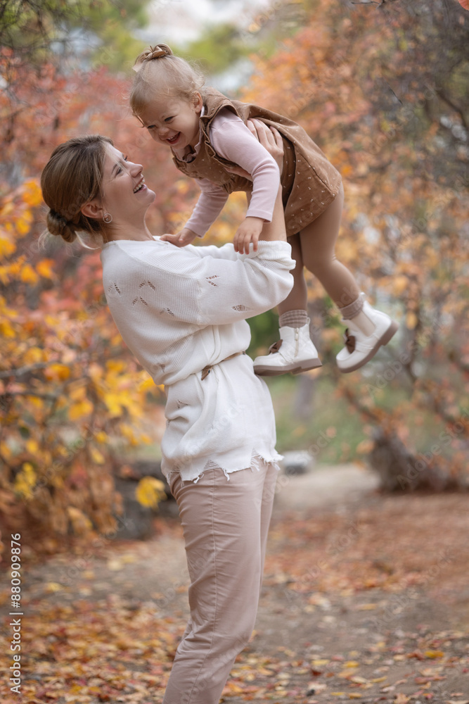woman lifts her daughter infante toldler 1-2 years old air. both smiling brightly. happy motherhood. autumn weekend family. surrounded by colorful fall leaves, creating warm and joyful scene. woman lifts her daughter infante toldler 1-2 years old air. both smiling brightly. happy motherhood. autumn weekend family. surrounded by colorful fall leaves, creating warm and joyful scene.