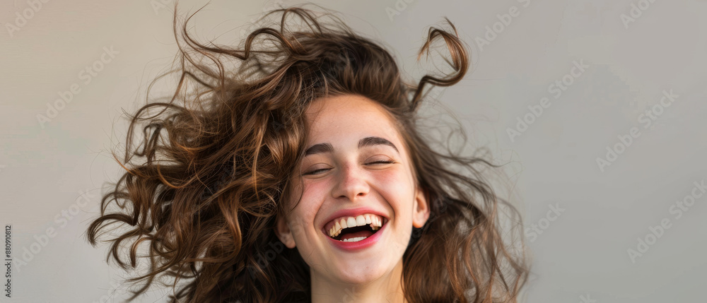 Φωτογραφία A young woman with tousled hair and a bright smile laughs joyfully, her lively energy virtually tangible through the photograph’s composition