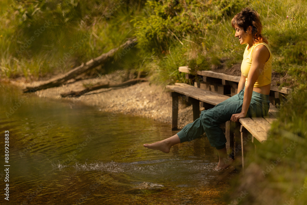 Fototapeta premium A woman is sitting on a bench by a body of water
