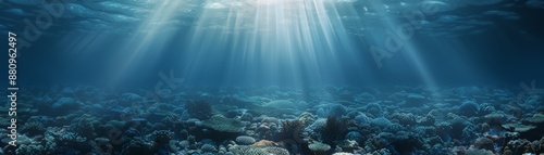 Sunlight beams penetrate clear blue ocean water, illuminating the rocky seabed and creating a serene underwater landscape.