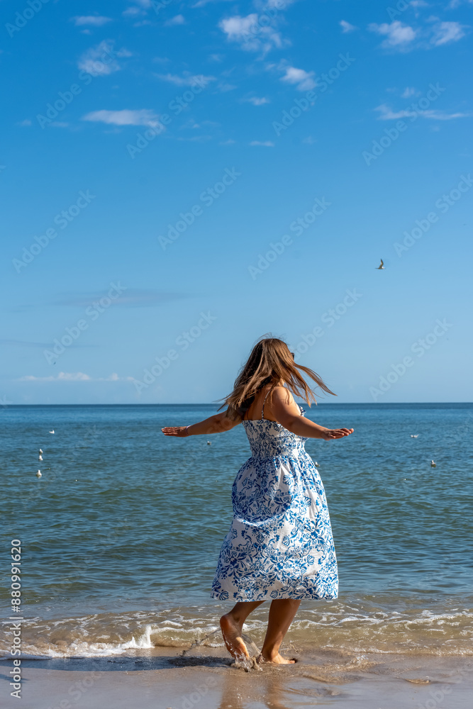 Woman in a dress dancing and twirling by the sea on a sunny day. Rest, relaxation, holidays. High quality photo Woman in a dress dancing and twirling by the sea on a sunny day. Rest, relaxation, holidays. High quality photo