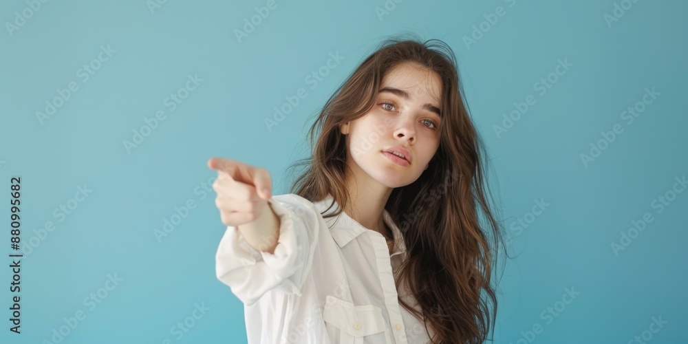 Fototapeta premium A woman in a white shirt points at the camera, focusing attention on her message