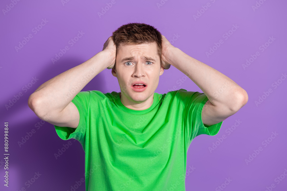 Photo of nice young man arms touch head wear t-shirt isolated on violet color background Photo of nice young man arms touch head wear t-shirt isolated on violet color background
