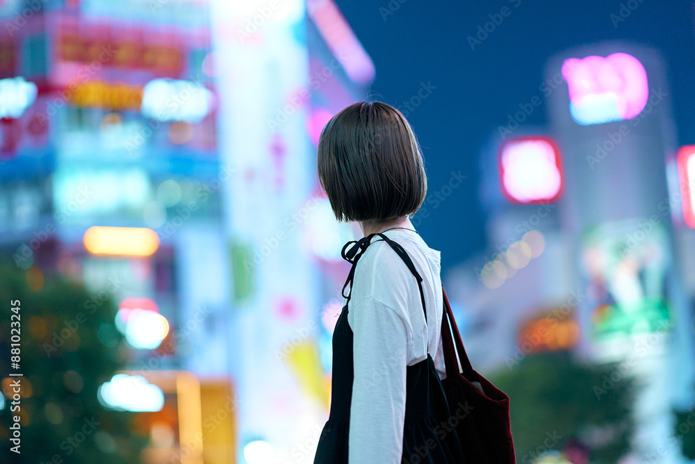 夜の繁華街を見つめる若い女性 夜の繁華街を見つめる若い女性