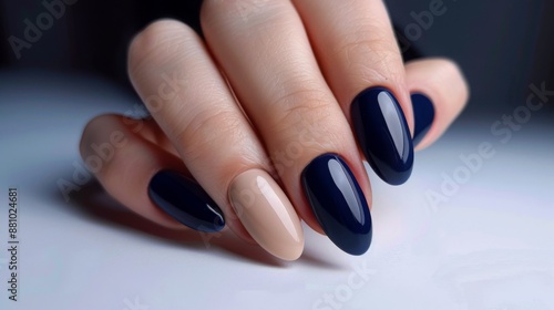 A woman's hand with several fingers painted in dark blue nail polish. The fingernails are shaped into an oval and have a glossy finish.