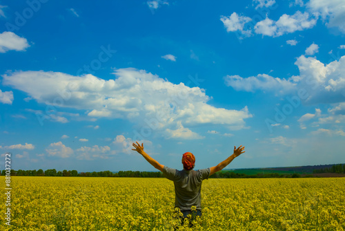 Fotografie happy man stay among yellow rape field under blue cloudy sky