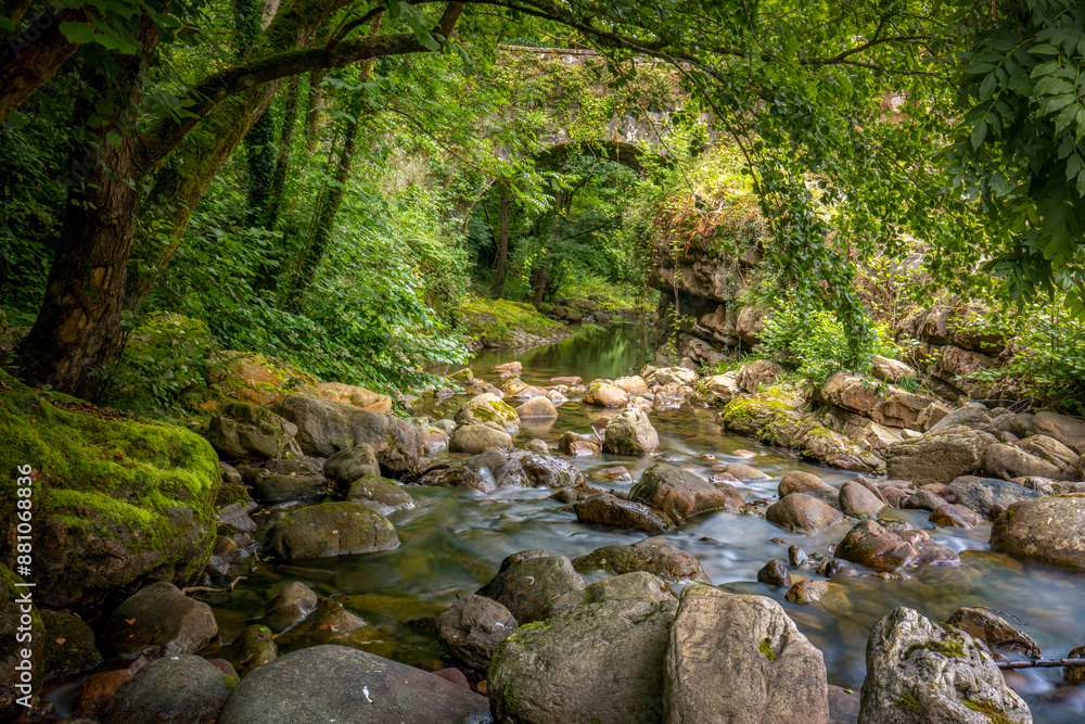 Argonza River as it passes through the medieval town of Bárcena Mayor, Cantabria, Spain, with rocks in its bed and a bridge in the background Argonza River as it passes through the medieval town of Bárcena Mayor, Cantabria, Spain, with rocks in its bed and a bridge in the background