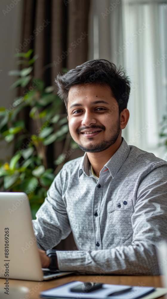 Young professional man smiling while working on laptop in modern office Young professional man smiling while working on laptop in modern office