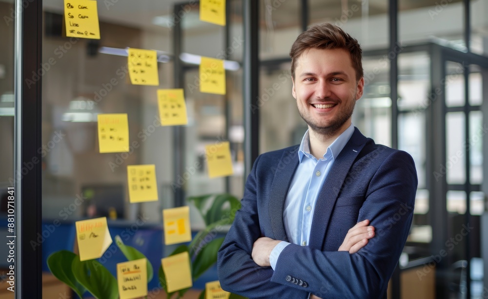 businessman in a suit smiling and standing with arms crossed on the glass wall of a modern office room businessman in a suit smiling and standing with arms crossed on the glass wall of a modern office room