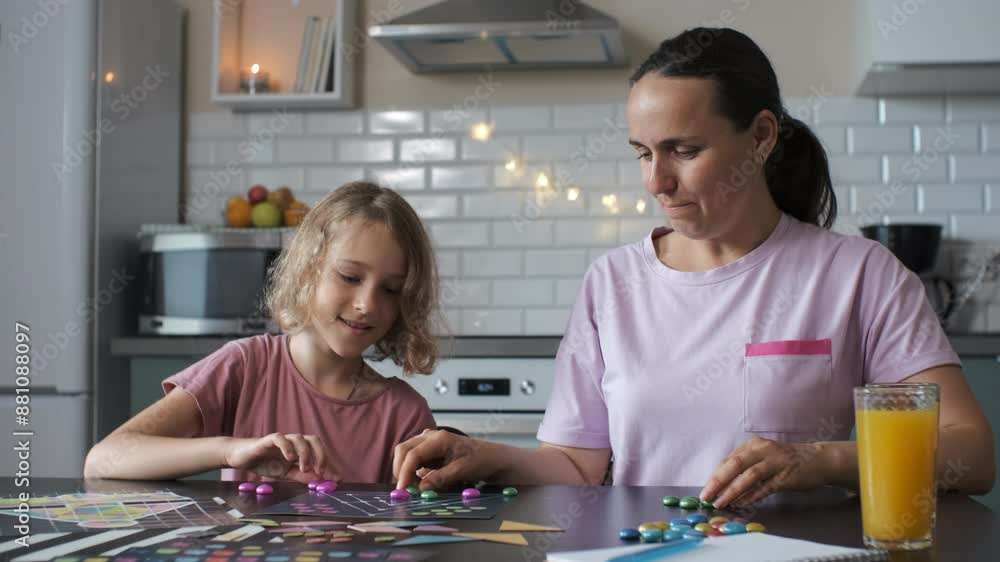 Enjoying quality time, cheerful young mother and her cute daughter play a board game in their kitchen, slow motion. Family lifestyle concept Enjoying quality time, cheerful young mother and her cute daughter play a board game in their kitchen, slow motion. Family lifestyle concept