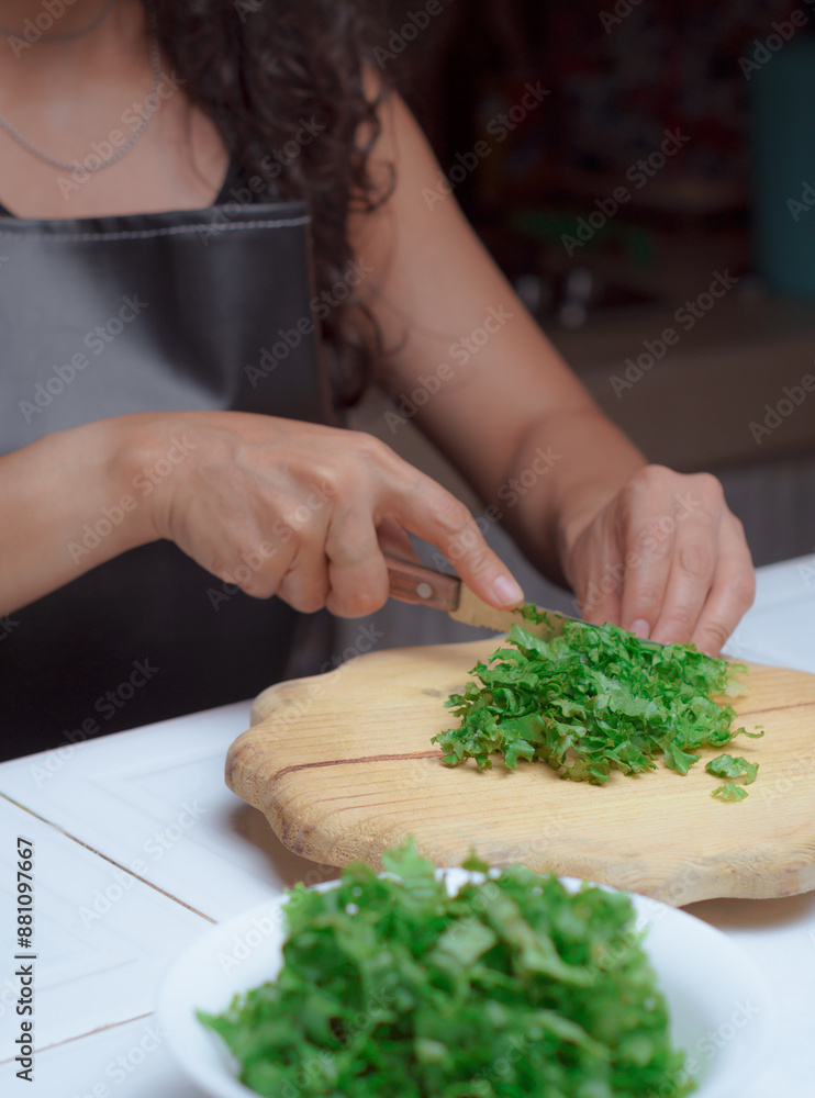 Hands of a cook with a knife cutting fresh lettuce leaves. Hands of a cook with a knife cutting fresh lettuce leaves.