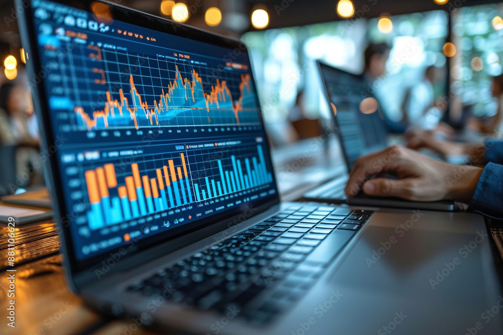 Business analysts collaborating on a financial report with laptops and charts Business analysts collaborating on a financial report with laptops and charts