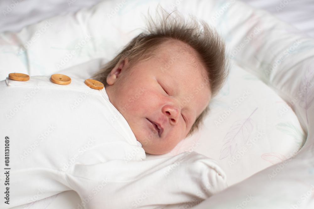 Caucasian newborn baby girl sleeping in the baby lounger in a white outfit. Baby sleep concept. Sleeping infant in a baby nest Caucasian newborn baby girl sleeping in the baby lounger in a white outfit. Baby sleep concept. Sleeping infant in a baby nest