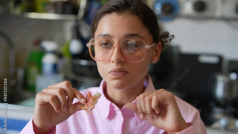 A stylish woman in a fashionable pink outfit and trendy glasses is happily snacking inside A stylish woman in a fashionable pink outfit and trendy glasses is happily snacking inside