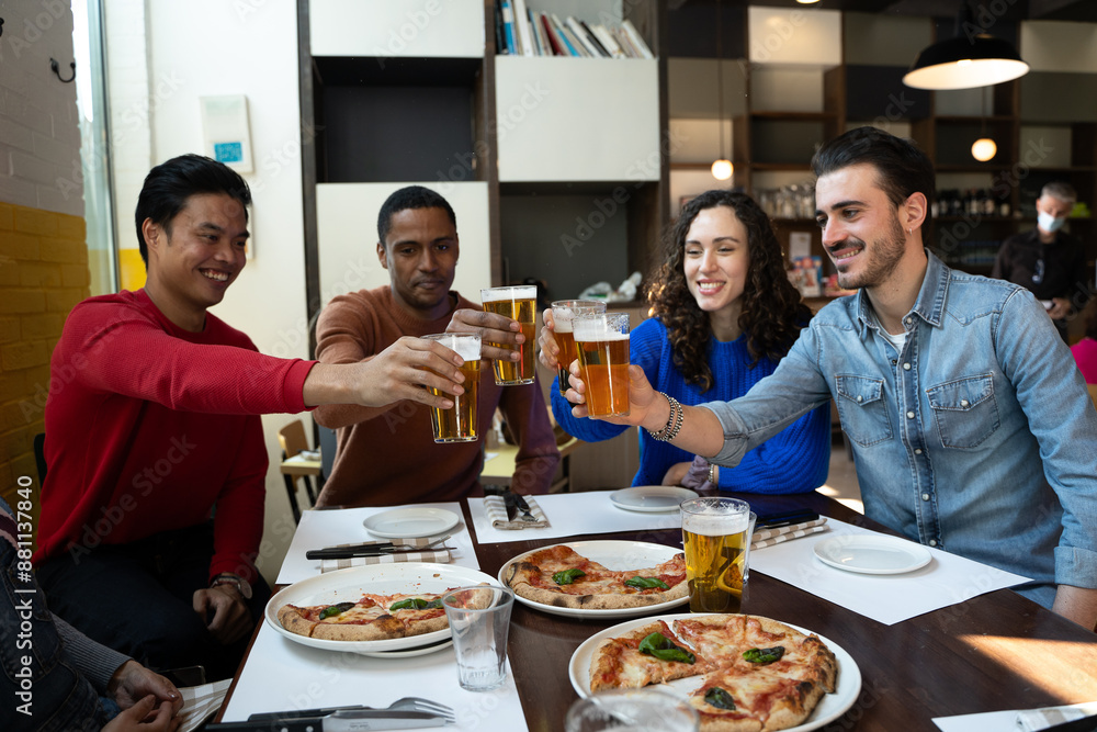 Group of friends is toasting with beer in pizzeria Group of friends is toasting with beer in pizzeria