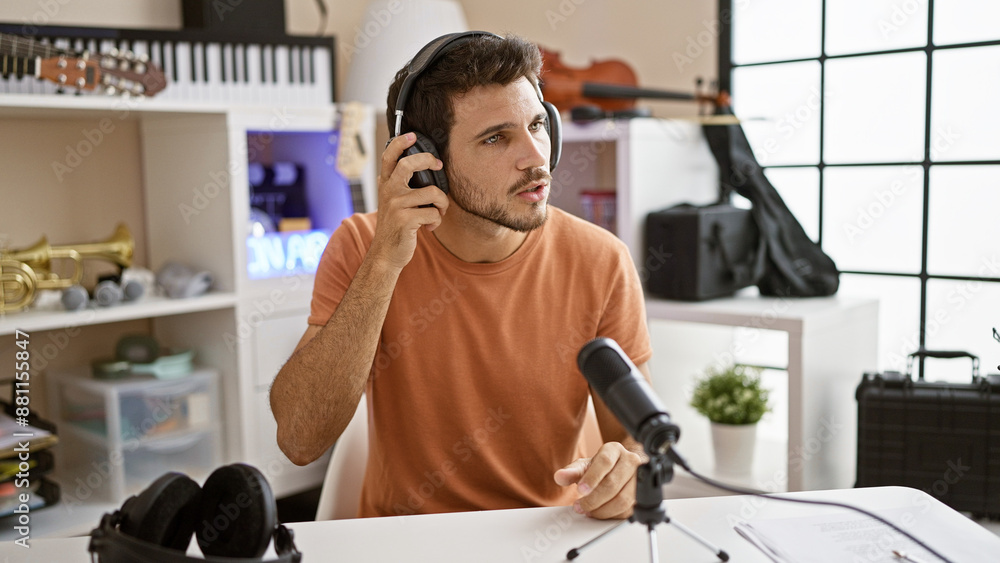 A focused hispanic man with a beard prepares for a podcast in a modern studio, adjusting his headphones. A focused hispanic man with a beard prepares for a podcast in a modern studio, adjusting his headphones.