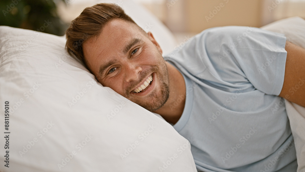 Handsome young man with beard smiling in cozy bedroom setting. Handsome young man with beard smiling in cozy bedroom setting.