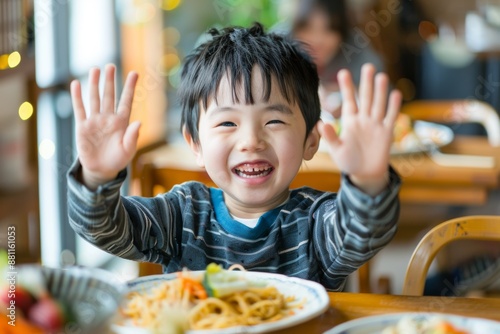 Natural light brightens cheerful boy's face breakfast. Cute kid displays innocent joy hands raised morning. Happy moments that reflect love and warmth of family life. photo