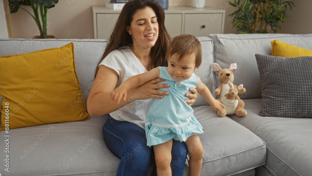 Woman sitting on a sofa holding her toddler with love in a cozy living room with yellow and gray cushions