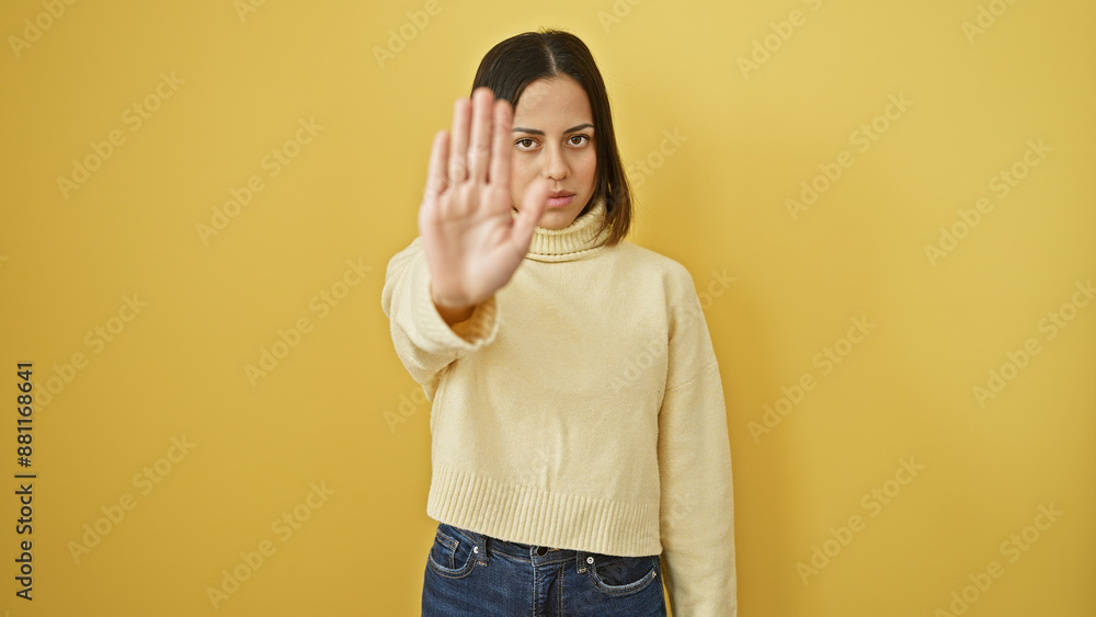 Hispanic young woman in a turtleneck signaling stop against a yellow wall expresses deniability. Hispanic young woman in a turtleneck signaling stop against a yellow wall expresses deniability.