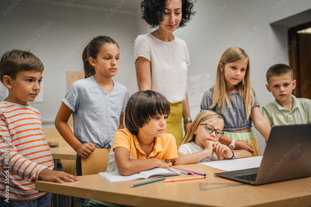 Mature teacher teach her students how to use laptop in the classroom Mature teacher teach her students how to use laptop in the classroom