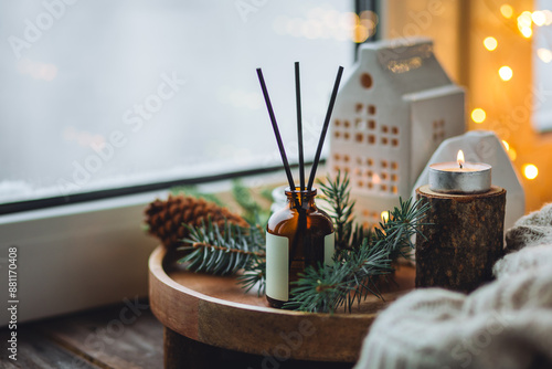 Natural Christmas essential oil, home aroma diffuser. Burning candles, branches of fir tree. Cinnamon, vanilla smell. Aromatherapy, cozy atmosphere, holiday festive mood. Close up macro, wooden table photo