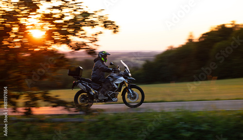 Driver riding motorcycle on empty road during sunset