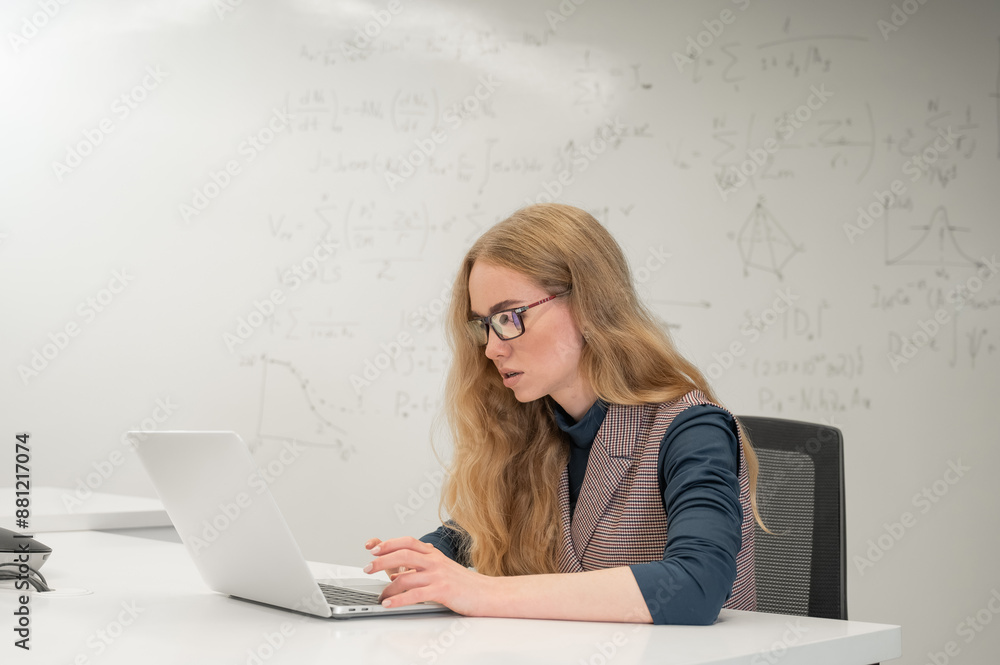 Caucasian woman scientist typing on laptop. White board with formulas. Caucasian woman scientist typing on laptop. White board with formulas.