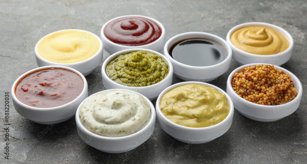 Many different sauces in bowls on grey table