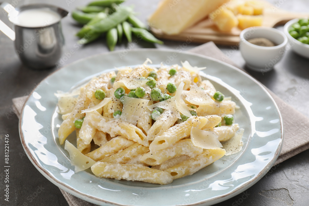 Delicious pasta with green peas, cheese, creamy sauce and ground pepper on grey table Delicious pasta with green peas, cheese, creamy sauce and ground pepper on grey table