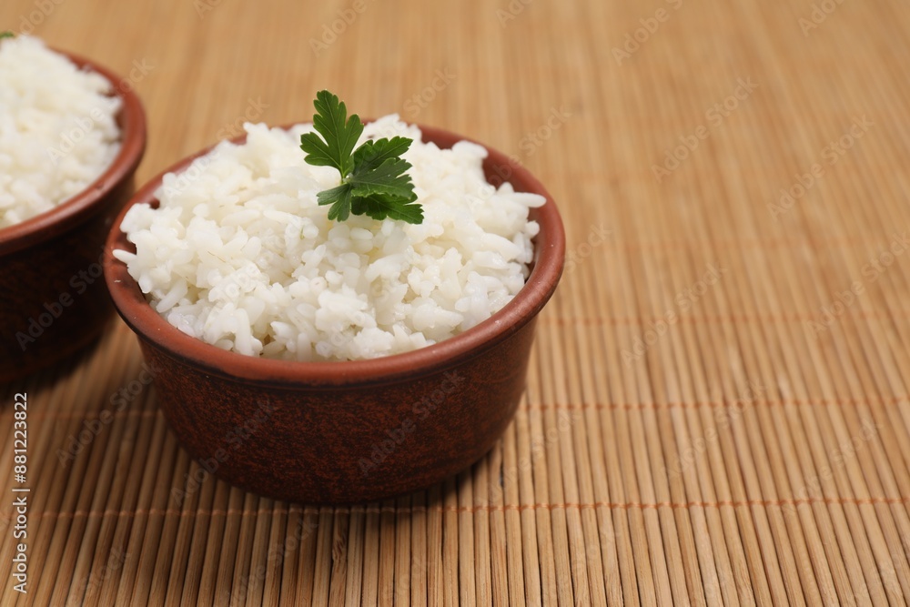 Bowls of delicious boiled rice with parsley on bamboo mat. Space for text Bowls of delicious boiled rice with parsley on bamboo mat. Space for text