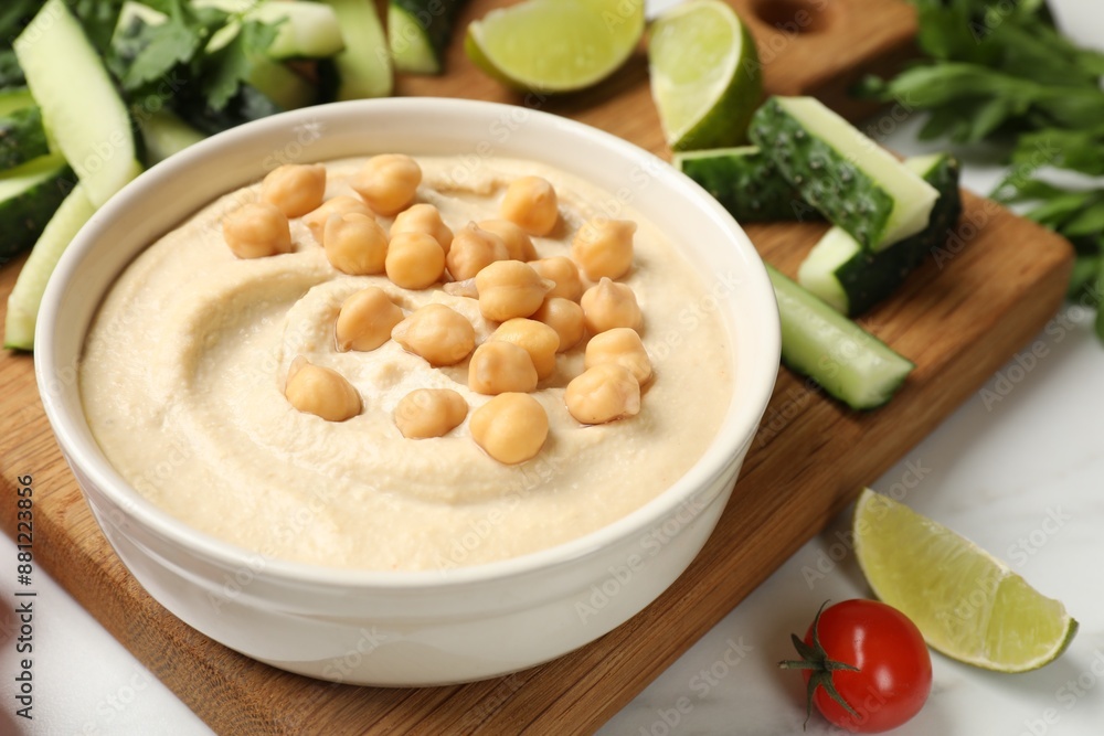 Tasty hummus with chickpeas in bowl and fresh products on light table, closeup Tasty hummus with chickpeas in bowl and fresh products on light table, closeup