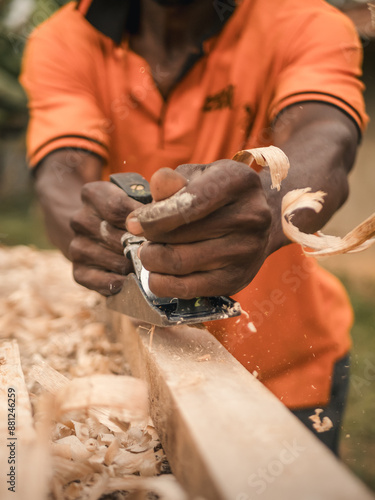 Carpenter using a hand plane to smooth wooden surface.