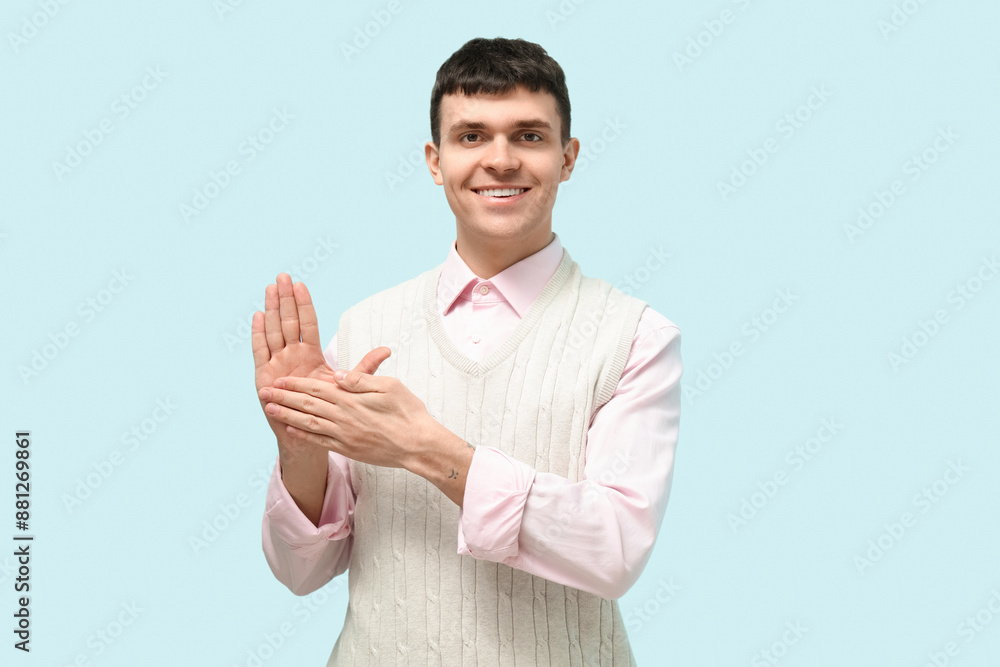 Young deaf mute man using sign language on blue background Young deaf mute man using sign language on blue background
