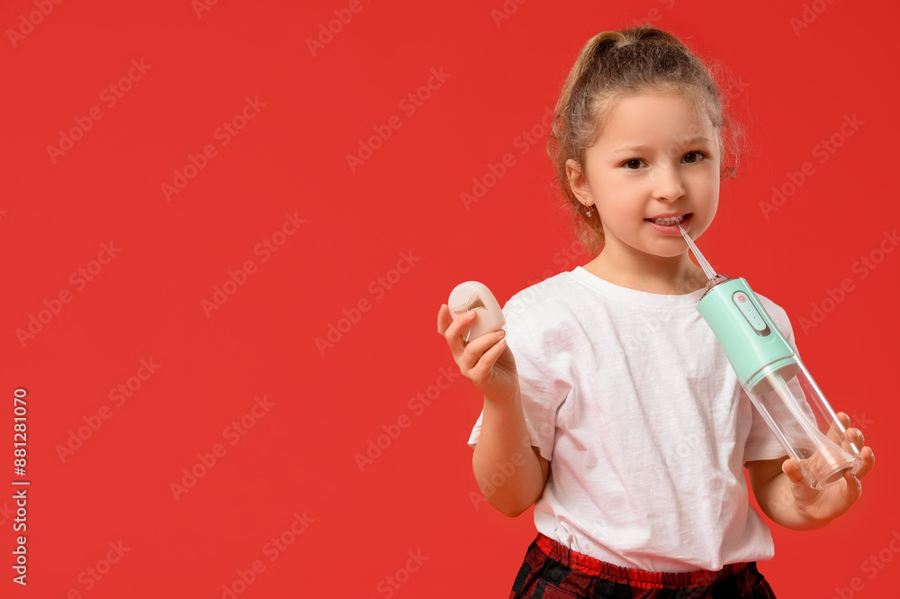 Cute little girl with oral irrigator and dental floss on red background Cute little girl with oral irrigator and dental floss on red background