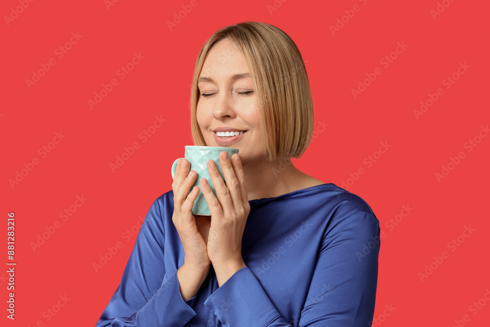 Happy adult woman with cup of coffee on red background Happy adult woman with cup of coffee on red background