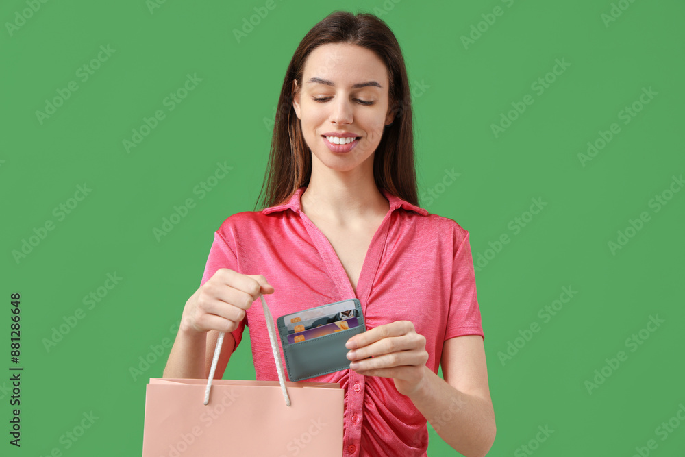 Beautiful young woman with credit card holder and shopping bag on green background Beautiful young woman with credit card holder and shopping bag on green background