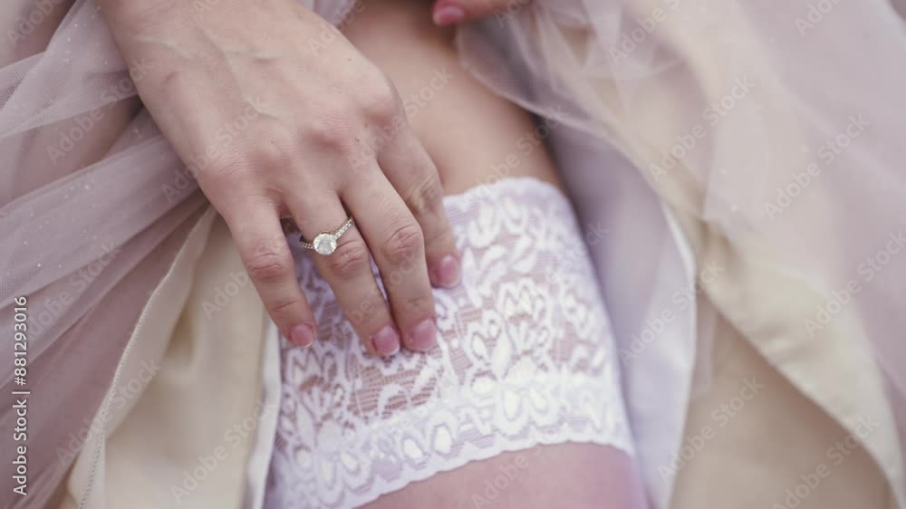 Sexy brunette woman in a wedding dress is adjusting white stockings, slow motion