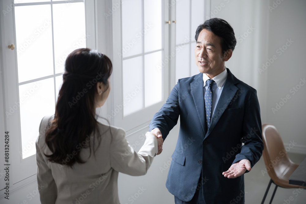Profile of an executive businessman and a salesman shaking hands at a contract or business meeting. Profile of an executive businessman and a salesman shaking hands at a contract or business meeting.