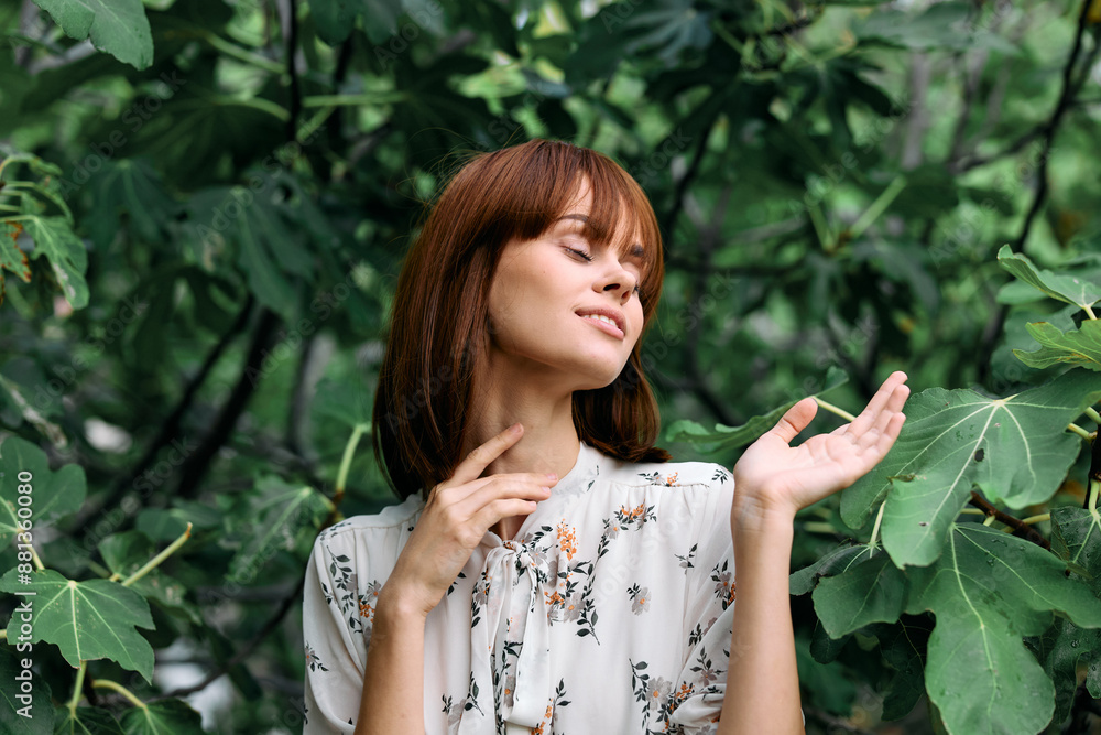 Happy woman standing in front of lush green leaves with hands on chest and smile