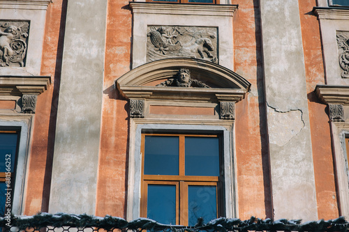 Old decorative architecture of Lviv, Ukraine.Windows on the red facade of a house in the central historical part of the city.Stucco molding and relief with Neptune (Poseidon) with a trident and horses photo