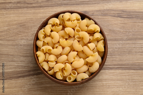 Raw macaroni pasta in bowl on wooden background, Food ingredient, Table top view